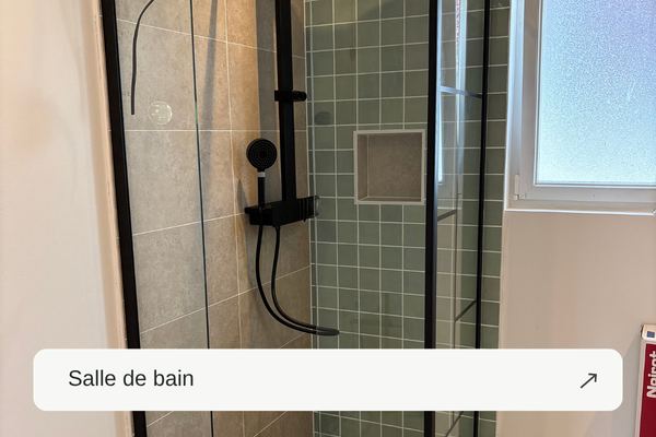Douche avec paroi vitrée, robinetterie noire et carrelage vert