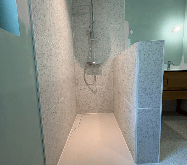 Espace douche avec receveur blanc et muret de séparation carrelé