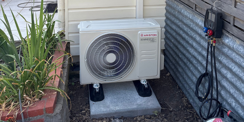 Unité extérieure de climatisation posée sur des supports au sol