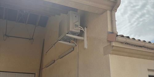 Unité extérieure de climatisation fixée en hauteur sur une façade